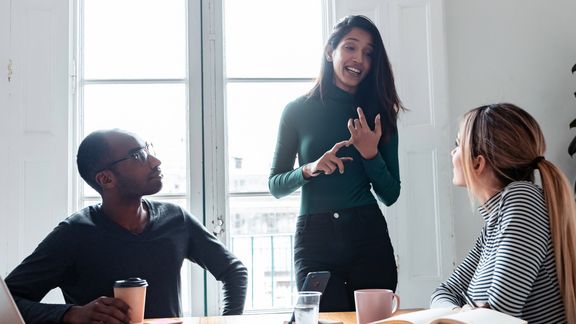 Eine Ausbilderin gibt 2 jungen Azubis Feedback