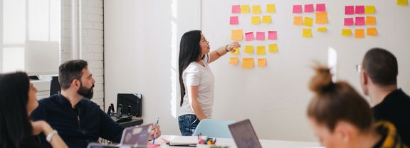 Eine Gruppe von Mitarbeitenden sitzen zusammen und diskutieren