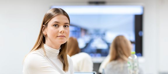 Azubine sitzt im Klassenzimmer und schaut in die Kamera