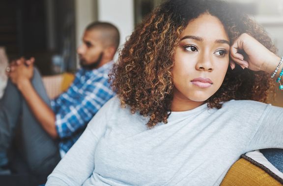 Eine traurige junge Frau schaut aus dem Fenster