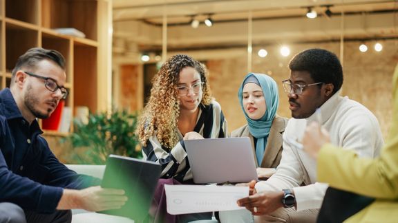 4 junge Menschen sitzen in einem Raum und arbeiten an einem Projekt
