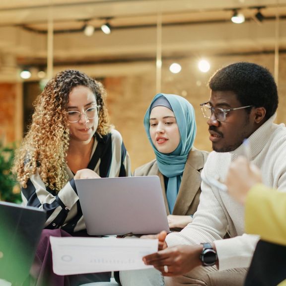 4 junge Menschen sitzen in einem Raum und arbeiten an einem Projekt
