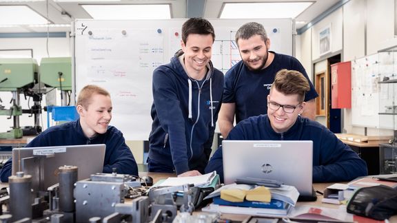 Lachende Azubis hinter einem Laptop