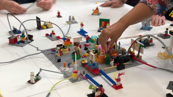 Lego-Modelle werden gemeinsam auf Tisch gebaut.