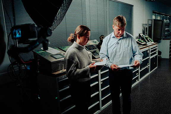 Szenerie einer Videoproduktion, Ausbildungsleiter schaut auf Dokument