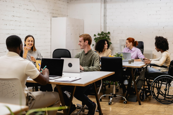 Diverse Gruppe sitzt an Schreibtischen und arbeitet