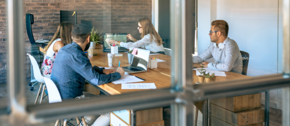 Vier Personen im Meetingraum bei kreativer Teamarbeit